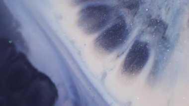 Parıldayan mürekkep dökülüyor. Işıl ışıl. Odaklanmamış mavi mor renkli parlak pigment sıvısı soyut sanat arkaplanda yüzüyor..