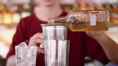 Karışım uzmanı işi. Jigger kullanarak. Barmen bardağa alkollü sıvı dolduruyor. Buzlu taze kokteyl için aroma şurubu ölçülüyor.