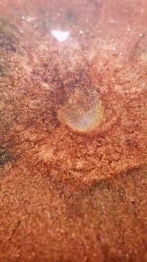 Dikey video. Parıltı sıçraması. Sıvı dökülmesi. Bulanık altın sarısı mürekkep rengi parlak baloncuklar soyut koyu mavi arkaplan üzerinde yüzen sıvı..