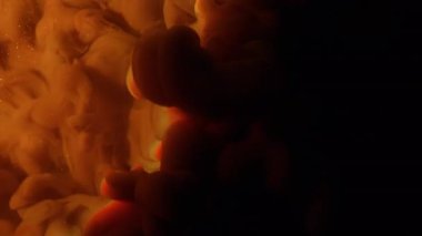 Mürekkep karışımı. Renkli bulut dokusu. Odaklanmamış turuncu pembe sıçrama gökkuşağı simli su soyut koyu siyah arka planda yayılıyor..