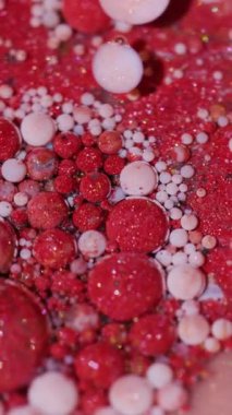 Dikey video. Yağ sıvısı. Boya sanatı. Bulanık kırmızı pembe beyaz renk ıslak lekeler sarı damlacıklar soyut akrilik arka planda yayılıyor.