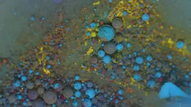 Boya akışı. Köpüklü yağ mürekkebi. Soyut akrilik arka planda çözünmüş sarı mor renkli simli baloncuk karışık su çemberi.