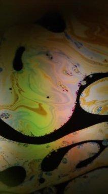 Dikey video. Çoklu renk sıvısı çözüldü. Boya balonu. Yağlı karışım, siyah suyun üzerinde ışık patlaması yaratır. Soyut damla sıvısı sanat köpüğü arkaplanı.