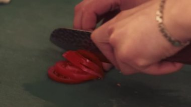 Yemek kesmek. Vejetaryen mutfağı. Şef mutfak masasında taze kırmızı domates dilimliyor. Salat kasesi bölümüne besin maddeleri yerleştiriliyor..