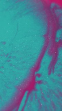 Dikey video. Mürekkep parlatıcısı. Akan sıvı. Soyut akrilik arka planda yüzen bulanık mavi pembe mor parlak desen sıvısı.