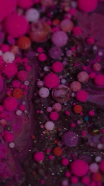 Dikey video. Yağ dokusu. Canlı mürekkep. Soyut akrilik arka planda yüzen mor, kırmızı renkli, köpüklü su damlacıkları..