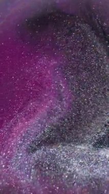 Dikey video. Odaklanmamış çember sıvısı. Mürekkep sıçraması. Bulanık mor renkli kimyasal simler soyut koyu siyah arkaplan üzerine damlacıklar.