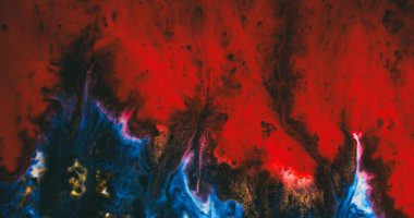 Boya akışı. Odaklanmamış sanat dokusu. Kırmızı dalga siyah mavi akrilik sıvının üzerine dökülüyor. Soyut arkaplanda altın rengi pigment karışımı.