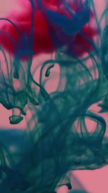 Dikey video. Mürekkep atışı. Duman girdabı. Pembe turkuaz pigmentler damlayan renkli su buharı sıçrama karışımı. Sanat boya damlası soyut sıvı arkaplan akışı.