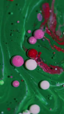 Dikey video. Yağ damlası. Sıvı arka plan. Bulanık yeşil pembe pembe mürekkep mermer beyaz su yuvarlak doku sanat soyutlaması üzerine akan.