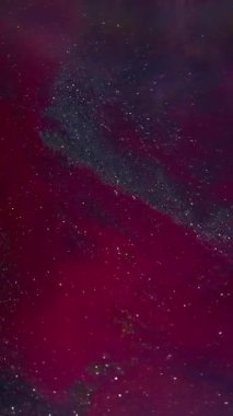 Dikey video. Akan boya. Bulanık parlak doku. Odaklanamayan kırmızı, mavi renkli su simleri soyut koyu siyah arkaplanda yüzüyor..