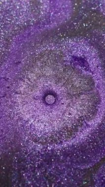 Dikey video. Parlak serpinti. Sıvı dökülmesi. Odaklanmamış mor eflatun renkli mürekkep parlatıcısı soyut koyu siyah arkaplana yayılan baloncuk deseni sıçratır.