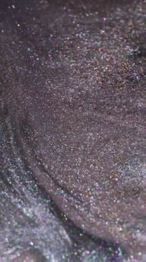 Dikey video. Sıçrama sanatı. Karışık doku. Bulanık beyaz mürekkep rengi kimyasal ışıldayan parçacıklar soyut akrilik arka plana dökülüyor.