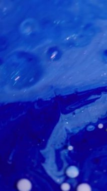 Dikey video. Yağ damlası. Sıvı arka plan. Bulanık mavi beyaz mürekkep mermer rengi parlak su yuvarlak doku soyutlama üzerine akan.