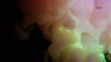 Mürekkep sisi. Gökkuşağı bulutu sıçraması. Odaklanmamış pembe mor parıltılı su parlak neon buhar soyut koyu siyah sanat arka planına yayılıyor..