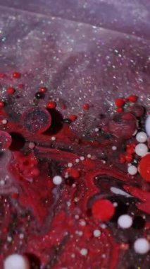 Dikey video. Köpüklü sıvı. Damla dokusu. Soyut akrilik zemin üzerinde yüzen odaksız kırmızı beyaz renk baloncukları mürekkep akışı.