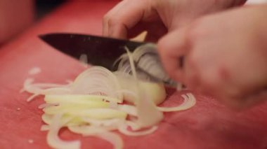 İşlem hazırlanıyor. Mutfak tekniği. Şef profesyonel olarak kırmızı pano restoranının mutfağında beyaz soğanı bıçakla doğruyor..