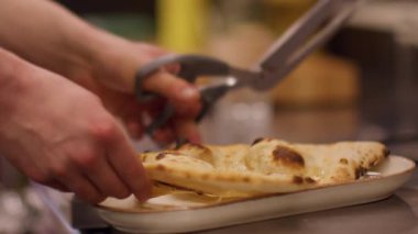 Dilimleme tabağı. Mutfak makası. Fırıncının eli çıtır çıtır taze ekmek pide kabuğunu parça parça servis ediyor. Profesyonel restoran metal aletleri..