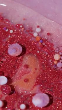 Dikey video. Parlak akış. Mürekkep döküldü. Soyut sanat arka planında yüzen mor su damlacıkları üzerinde odaklanmış kırmızı mavi parlak yağ rengi..