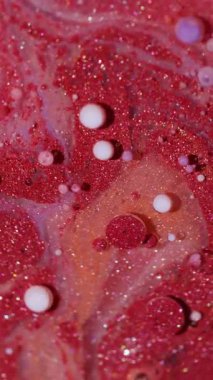 Dikey video. Mürekkep parçacıkları. Suyu boya. Odaklanmamış kırmızı mor turuncu renkli parlak yağ beyaz damlacıklar soyut arkaplanda yüzen parlak sıvılar.