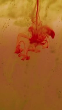 Dikey video. Mürekkep atışı. Duman girdabı. Turuncu sarı pigmentler damlayan su bulanıklığı karışımı. Sanat parçacıkları soyut sıvı arkaplan lekesi boyar.