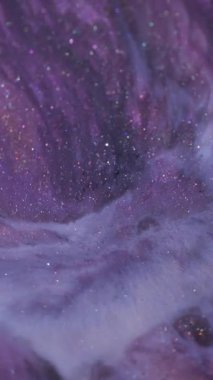 Dikey video. Dökme mürekkebi. Parlak sıvı. Soyut arkaplanda yüzen odaksız mor mavi renk sim dokusu ıslak parçacıklar.