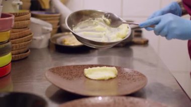 Tabak yiyeceği. Ezilmiş patates servis ediyorum. Şefin eli eldivenli, yumuşak sebze yemeği koyuyor. Restoran mutfağının siparişi hazırlanıyor..