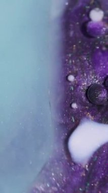 Dikey video. Mürekkep karışımı. Petrol emülsiyonu dökülüyor. Odaklanmamış mor mavi renkli köpük köpükleri soyut arkaplanda parlıyor..