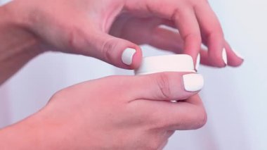 Deri gıdası. Krema kavanozu. Beyaz arka planda merhem kutusu açan kadın elleri. Kadın nemlendirici, kozmetik günlük güzellik uyguluyor.