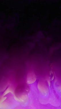 Dikey video. Parlak mürekkep. Odaklanamayan akış. Pembe mor menekşe patlama dalgası bulanık renk karışımı. Neon parıltısı siyah su arka planında yayılıyor.