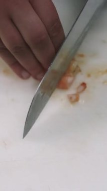Dikey video. Karides doğrama. Deniz mahsulleri pişiriyorum. Şef, beyaz mutfak tahtasına keskin bir bıçakla soyulmuş malzemeyi doğruyor. El kıyma tekniği..