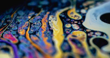 Mürekkep kabarcığı çözüldü. Spektrum sıvısı. Renkli köpüklü sıvı doku. Siyah arkaplanda sarı mavi soyut pigment damlası karışımı.