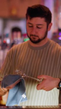 Dikey video. Barmenlik işi. Bar servisi. Neon ışıklı barda cam silip duran bir adam. Alkollü içeceklerin bardaklarını temizleyen işçi..