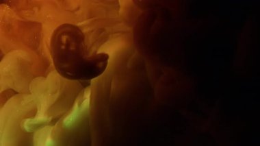 Duman dalgalarını boya. Parlak parçacıklar. Odaklanmamış turuncu yeşil renkli parlak gökkuşağı bulutu soyut koyu siyah arka planda yayılıyor..