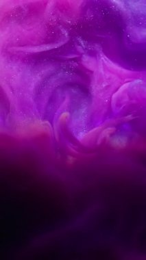 Dikey video. Parıltı akışı. Mürekkep girdabı. Pembe mor parlak akış siyah arkaplanda karışıyor. Odaklanamayan parlak gökkuşağı renginde ışık kemeri etrafında soyut su.