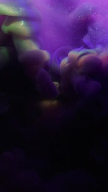 Dikey video. Mürekkep patlaması. Parıltı dalgası. Mor menekşe rengi duman, ışıldayan soyut ışına yayılmış. Siyah arkaplan, gökkuşağı merceği dumanı.