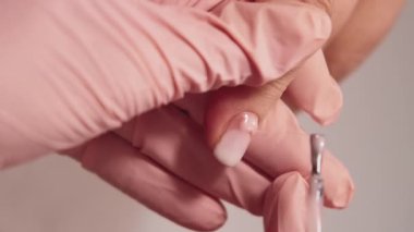 Dikey video. Profesyonel el bakımı. Donanım manikürü. Güzellik salonunda kadın kozmetoloji uzmanı tırnaklarını pastel jel cilasıyla kaplıyor..