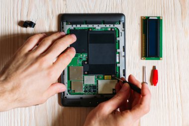 Technician repair tablet computer on wooden background