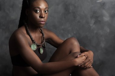 Yeşil kolye ile güzel bir siyah kadın oturur