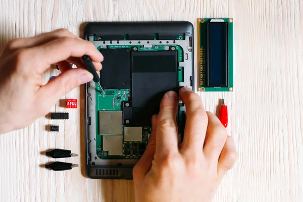 Technician repair tablet computer on wooden background — Stock Photo, Image