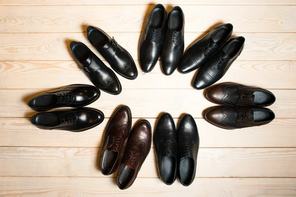 Many leather men's shoes on wooden background — Stockfoto
