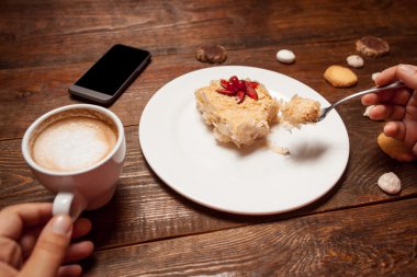  Unrecognizable person eating cake and drinking coffee