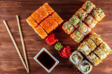 Somon ve füme yılan balığı ile suşi ruloları, Philadelphia peyniri, ahşap bir masada servis edilir.