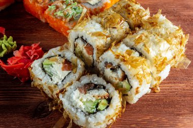 Somonlu suşi ruloları ve ahşap bir masada tütsülenmiş yılan balığı.