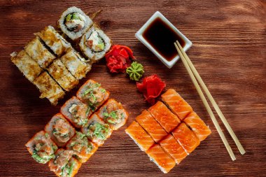 Somon ve füme yılan balığı ile suşi ruloları, Philadelphia peyniri, ahşap bir masada servis edilir.