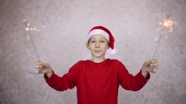 Kırmızı Noel Baba şapkalı ve maytaplı bir çocuk mutlu yıllar diler.