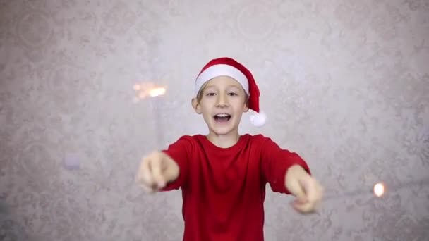 Ein Junge Mit Roter Weihnachtsmütze Und Wunderkerzen Wünscht Ein Frohes — Stockvideo