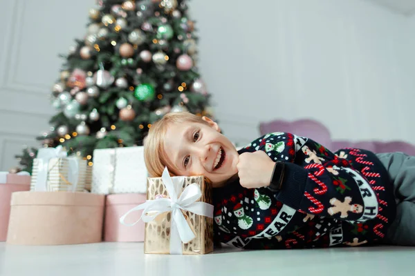 Egy Újévi Pulóveres Gyerek Fekszik Egy Karácsonyi Ajándékon — Stock Fotó