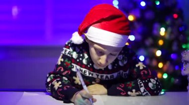 Arka planda, neon ışıklarının arkasında bir çocuk Noel Baba 'ya bir mektup yazıyor.