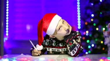 Arka planda, neon ışıklarının arkasında bir çocuk Noel Baba 'ya bir mektup yazıyor.